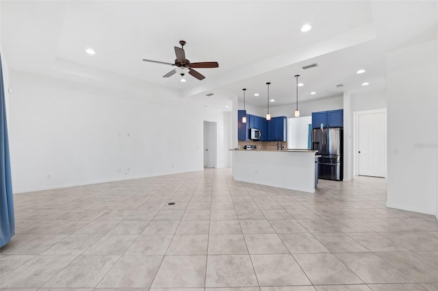 kitchen featuring blue cabinetry, ceiling fan, stainless steel appliances, a tray ceiling, and light tile patterned flooring