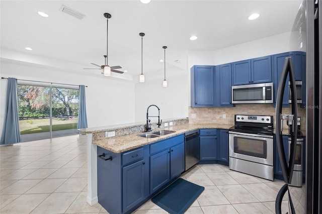 kitchen featuring sink, blue cabinetry, appliances with stainless steel finishes, light stone counters, and kitchen peninsula