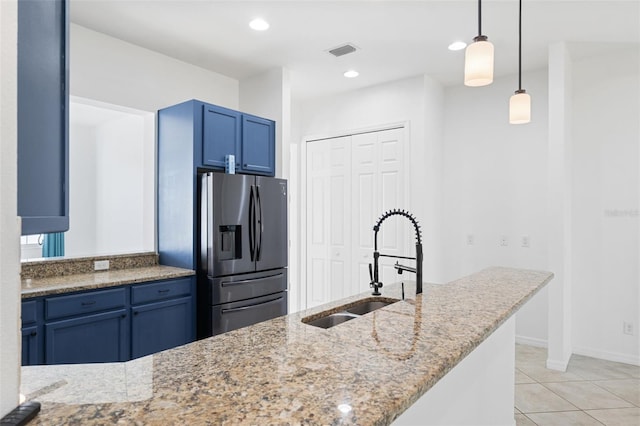 kitchen with light stone counters, sink, pendant lighting, and stainless steel refrigerator with ice dispenser