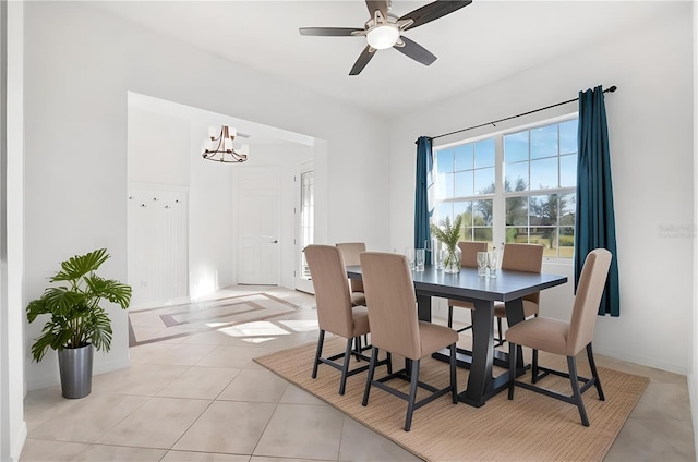 tiled dining space featuring ceiling fan with notable chandelier