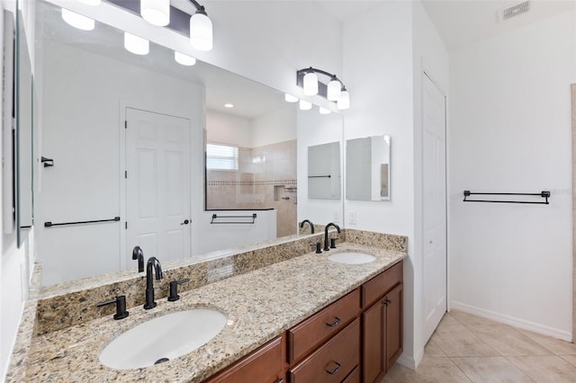 bathroom with tiled shower, vanity, and tile patterned flooring