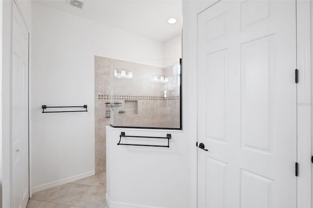 bathroom with tiled shower and tile patterned flooring