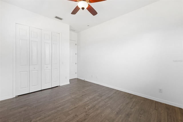 unfurnished bedroom with ceiling fan, a closet, and dark wood-type flooring