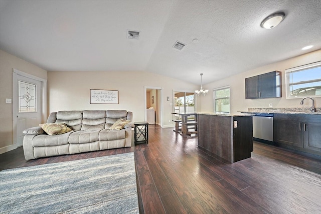 living room with a notable chandelier, dark hardwood / wood-style floors, a textured ceiling, and lofted ceiling