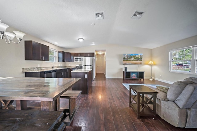 interior space with dark hardwood / wood-style flooring, stainless steel appliances, a center island, lofted ceiling, and dark brown cabinetry