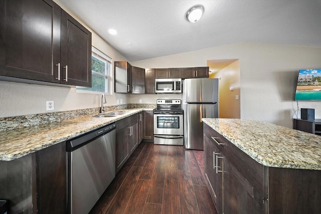 kitchen with lofted ceiling, dark wood-type flooring, stainless steel appliances, sink, and light stone counters