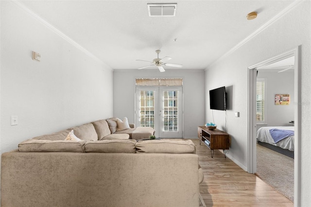 living room with ceiling fan, ornamental molding, french doors, and light hardwood / wood-style flooring