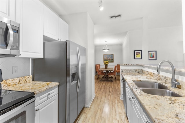 kitchen featuring appliances with stainless steel finishes, backsplash, sink, white cabinets, and light hardwood / wood-style floors