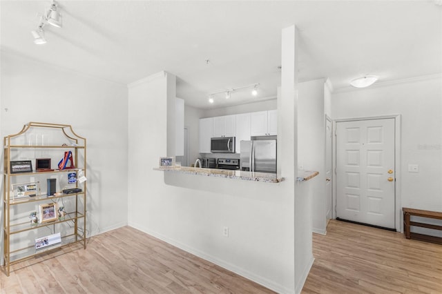 kitchen featuring white cabinetry, stainless steel appliances, light stone counters, kitchen peninsula, and light hardwood / wood-style floors