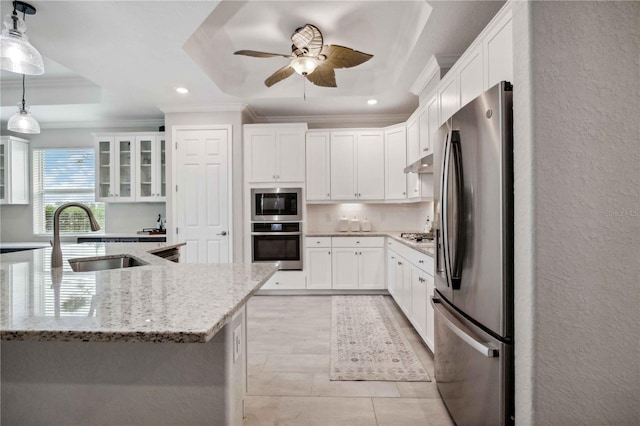 kitchen featuring a raised ceiling, crown molding, hanging light fixtures, appliances with stainless steel finishes, and white cabinetry