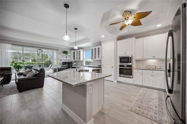 kitchen featuring light stone counters, a tray ceiling, stainless steel appliances, sink, and white cabinetry