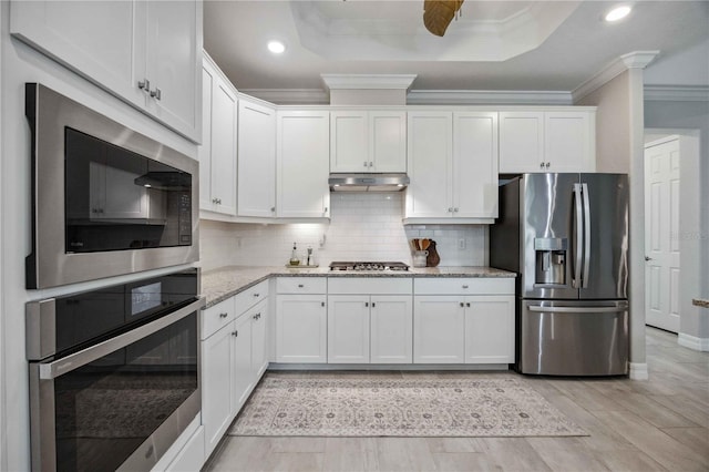 kitchen with backsplash, ceiling fan, light stone countertops, appliances with stainless steel finishes, and white cabinetry