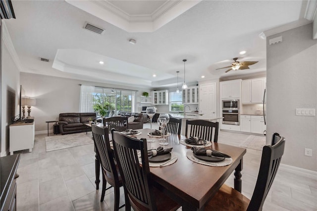 tiled dining area featuring a tray ceiling, ceiling fan, and ornamental molding