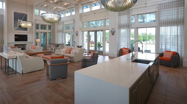 kitchen featuring sink, a high ceiling, a notable chandelier, pendant lighting, and a center island with sink