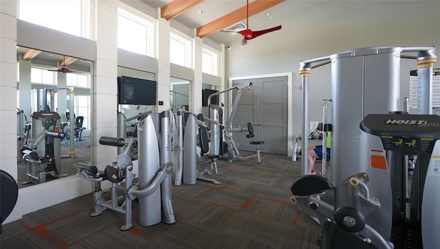 exercise room with a towering ceiling and dark carpet