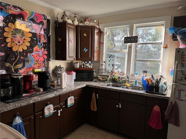 kitchen featuring dark brown cabinets, light stone countertops, light tile patterned flooring, crown molding, and sink