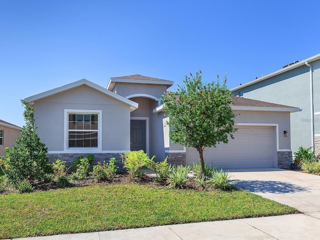 5719 Woodland Sage Dr, Sarasota, FL 34238 - view of front of home with stone siding, an attached garage, concrete driveway, stucco siding, and a front lawn
