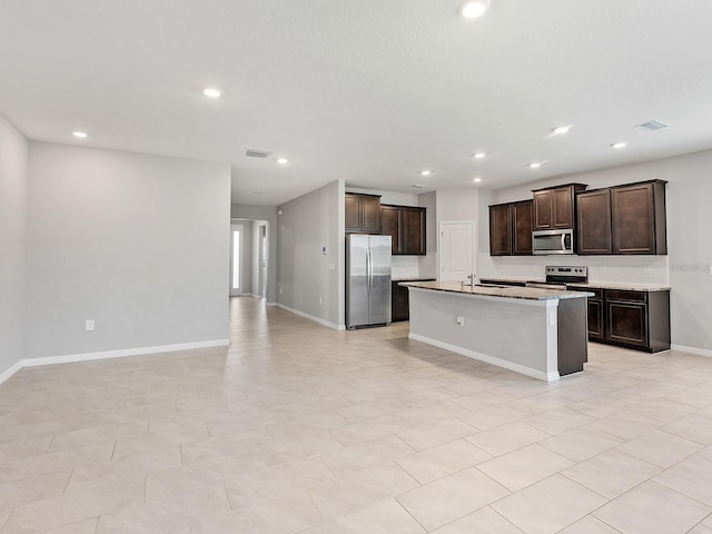 kitchen with visible vents, open floor plan, stainless steel appliances, baseboards, and dark brown cabinets