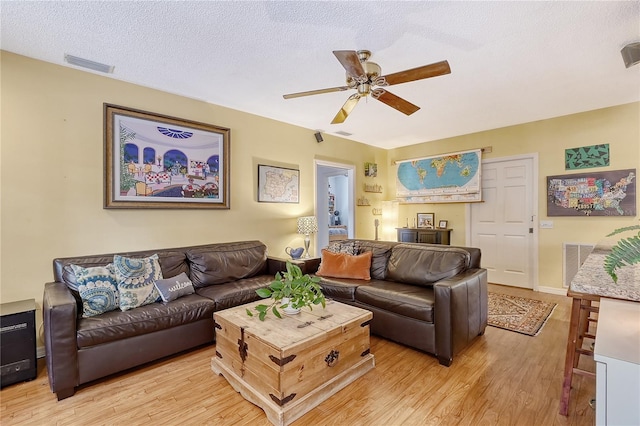 living room featuring light hardwood / wood-style floors, a textured ceiling, and ceiling fan