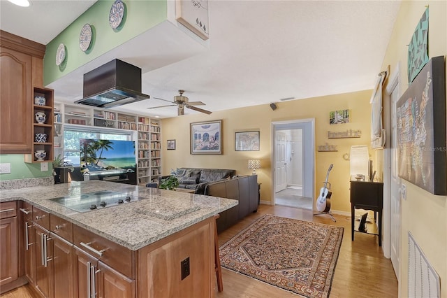 kitchen featuring light hardwood / wood-style floors, black electric stovetop, light stone countertops, and kitchen peninsula