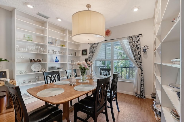 dining room featuring a textured ceiling and light hardwood / wood-style floors