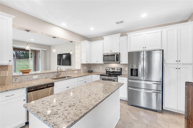 kitchen with hanging light fixtures, sink, white cabinets, appliances with stainless steel finishes, and tasteful backsplash