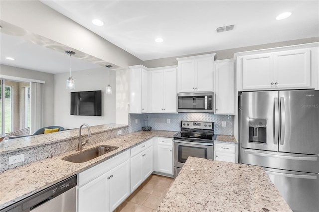 kitchen featuring stainless steel appliances, sink, light stone countertops, pendant lighting, and white cabinets