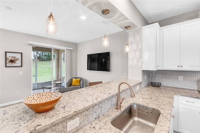 kitchen with light stone countertops, pendant lighting, and white cabinets