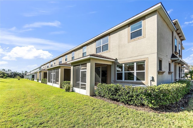 back of property with a yard and a sunroom