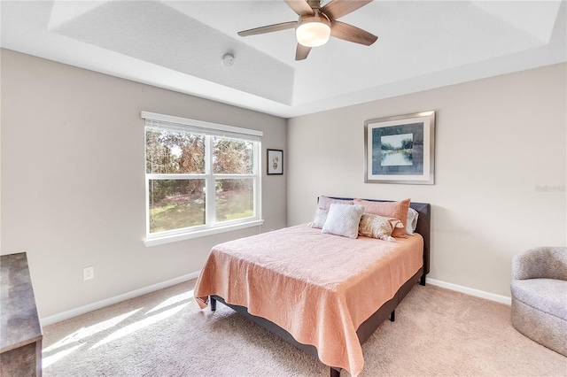 carpeted bedroom with a tray ceiling and ceiling fan