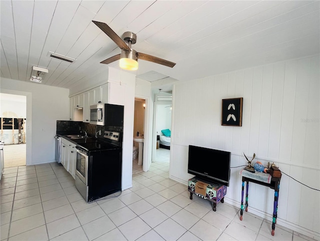 kitchen with stainless steel appliances, tasteful backsplash, light tile patterned floors, and white cabinets