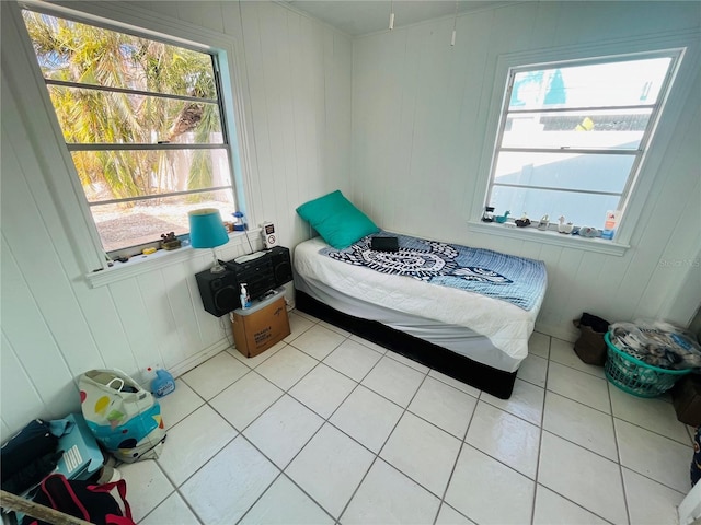 tiled bedroom with multiple windows and wooden walls