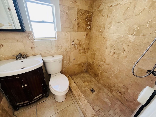 bathroom with tile walls, vanity, a tile shower, and toilet