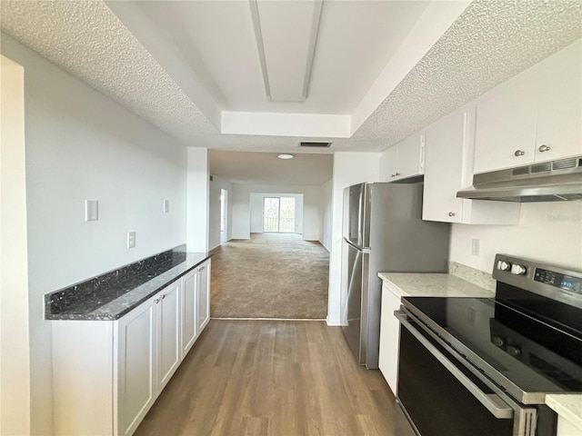 kitchen with electric range, white cabinetry, a textured ceiling, dark stone counters, and light hardwood / wood-style flooring