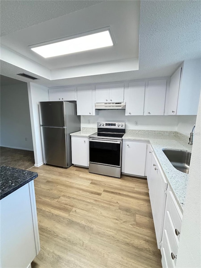 kitchen with appliances with stainless steel finishes, sink, light hardwood / wood-style floors, white cabinets, and light stone counters