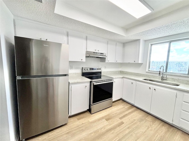 kitchen with a raised ceiling, white cabinetry, light hardwood / wood-style flooring, sink, and stainless steel appliances