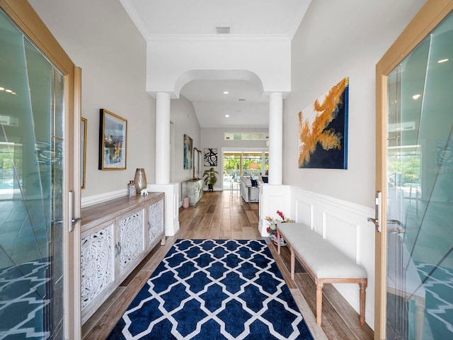 entrance foyer with crown molding, wood-type flooring, lofted ceiling, and decorative columns