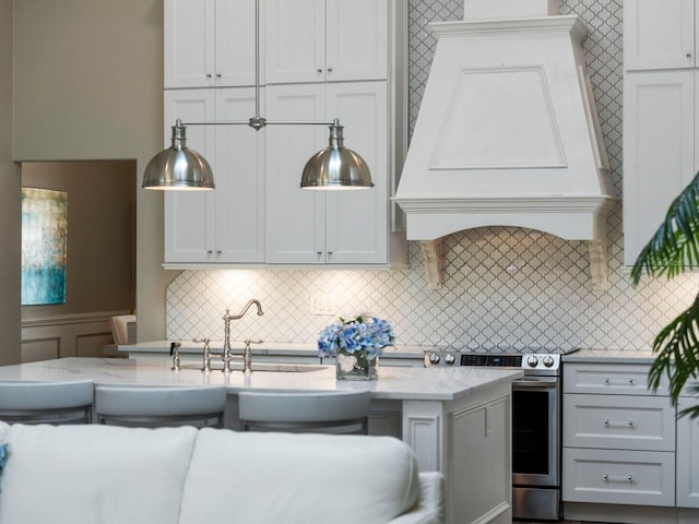 kitchen featuring sink, electric stove, light stone counters, decorative backsplash, and premium range hood