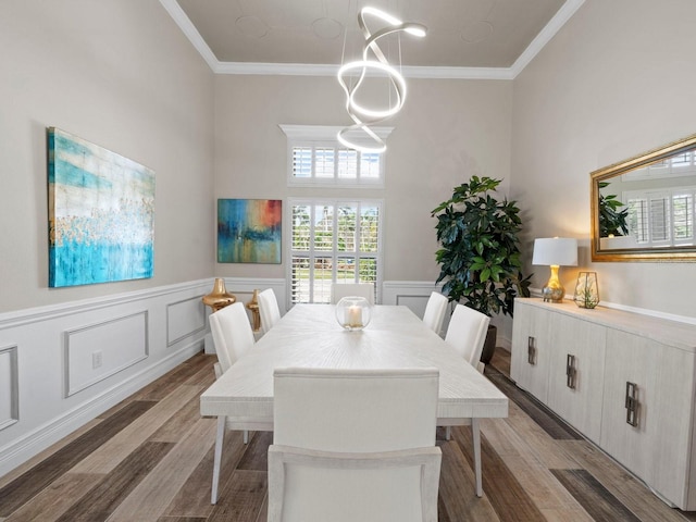 dining space featuring hardwood / wood-style floors, crown molding, and a high ceiling