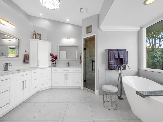 bathroom featuring vanity, independent shower and bath, vaulted ceiling, and a wealth of natural light