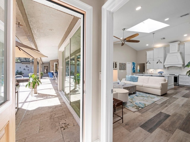 interior space with light hardwood / wood-style floors, vaulted ceiling with skylight, and ceiling fan