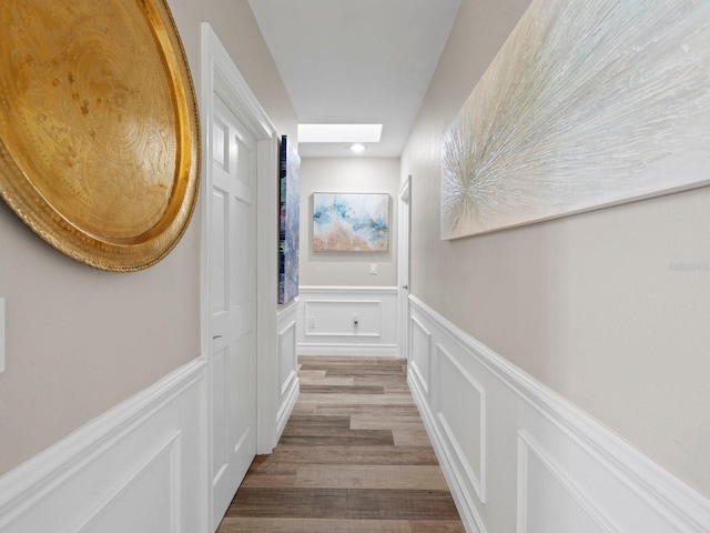 hallway with wood-type flooring and a skylight