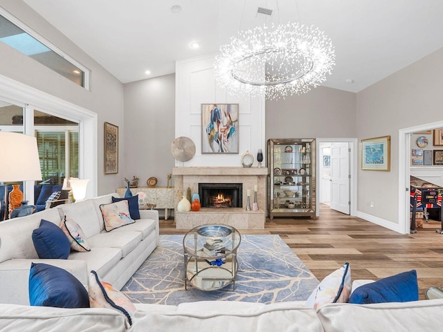 living room featuring hardwood / wood-style flooring, a chandelier, high vaulted ceiling, and a tiled fireplace