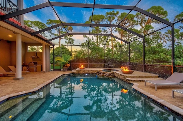 pool at dusk featuring glass enclosure, an in ground hot tub, and a patio area