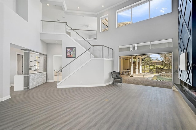 entrance foyer featuring plenty of natural light, hardwood / wood-style floors, ornamental molding, and a towering ceiling