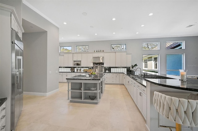 kitchen featuring white cabinetry, dark stone countertops, a kitchen bar, backsplash, and a kitchen island