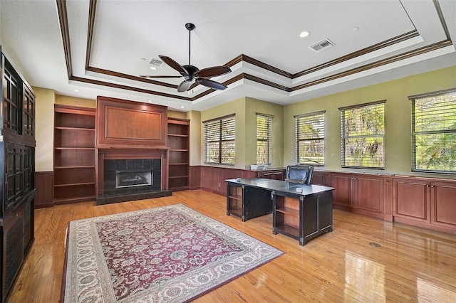 office space with a wealth of natural light, a tray ceiling, and light hardwood / wood-style flooring