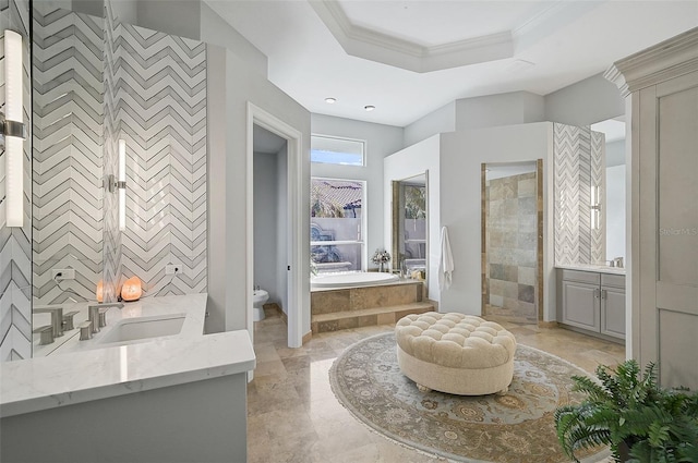 full bathroom with toilet, separate shower and tub, tile walls, vanity, and a raised ceiling