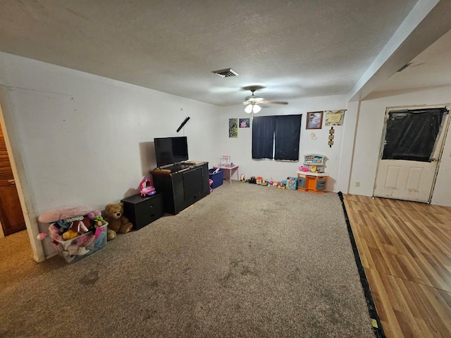 playroom with ceiling fan, a textured ceiling, and wood-type flooring