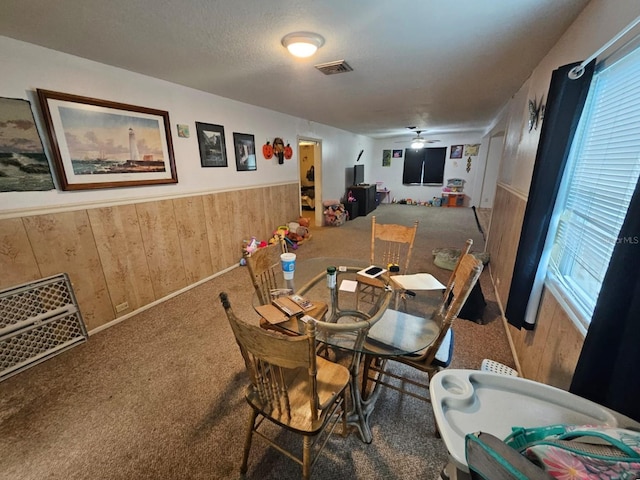 dining room featuring wood walls, carpet, and ceiling fan